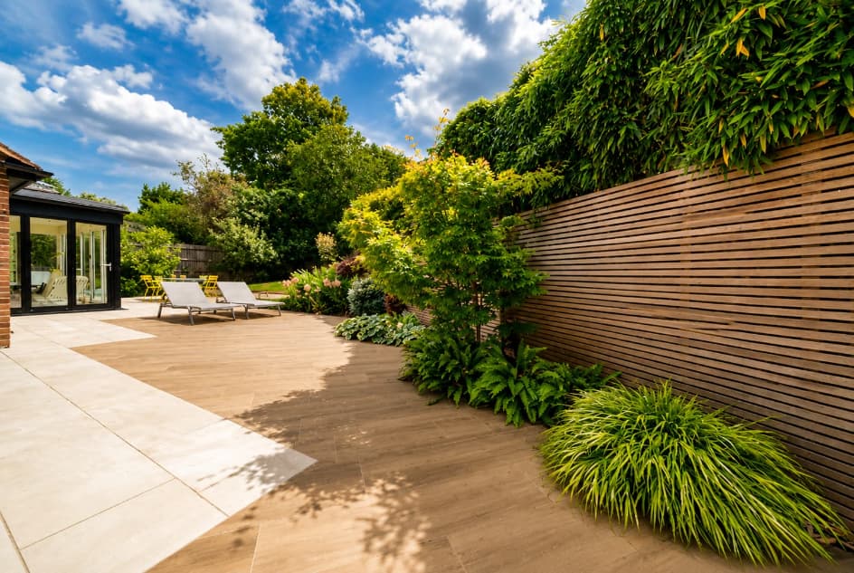 Contemporary garden with horizontal slatted timber fencing, landscaped planting and a spacious patio, creating a modern and private outdoor living space.